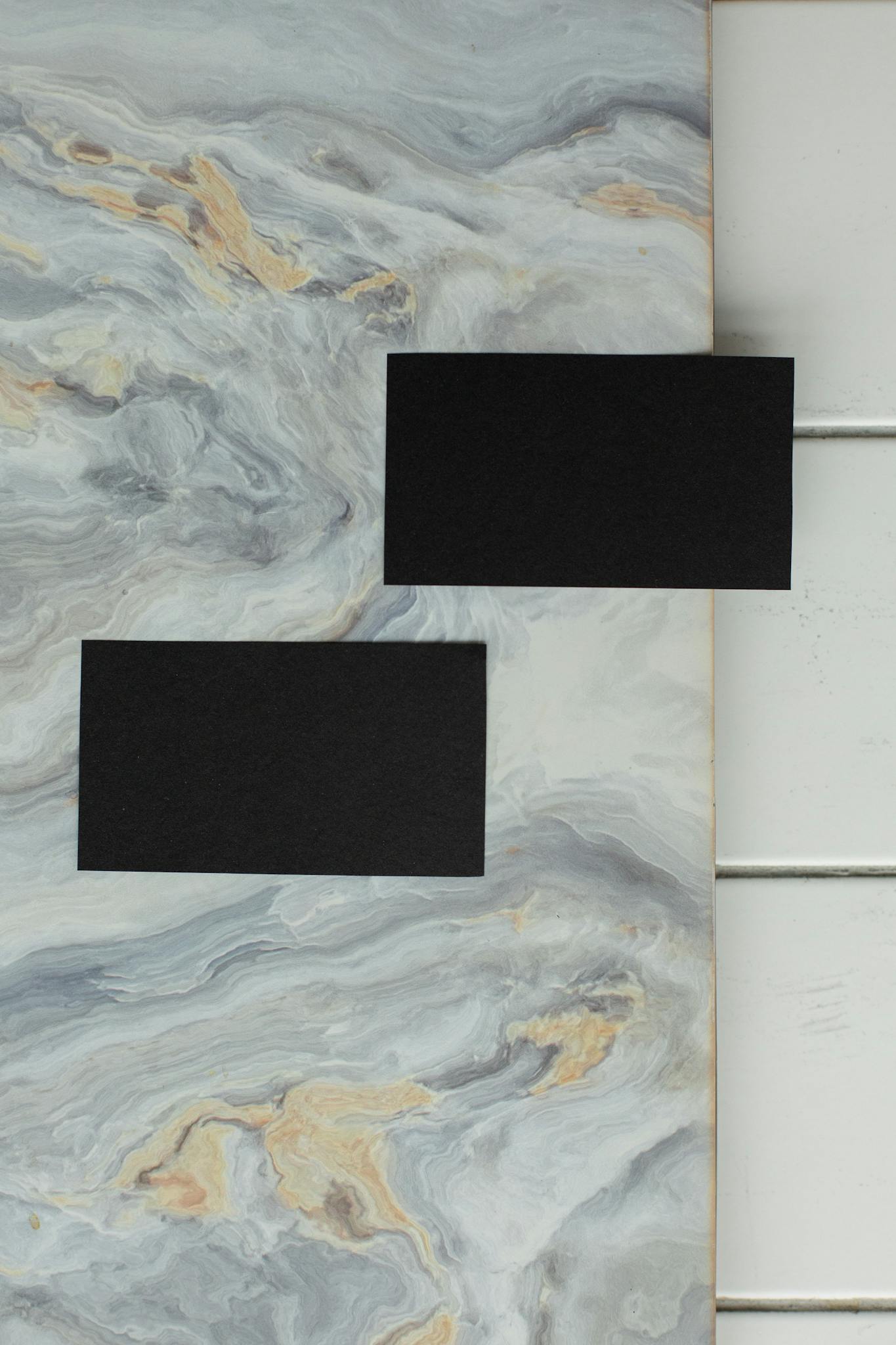 High-angle view of black cards placed over a marble background, perfect for minimalist business designs.
