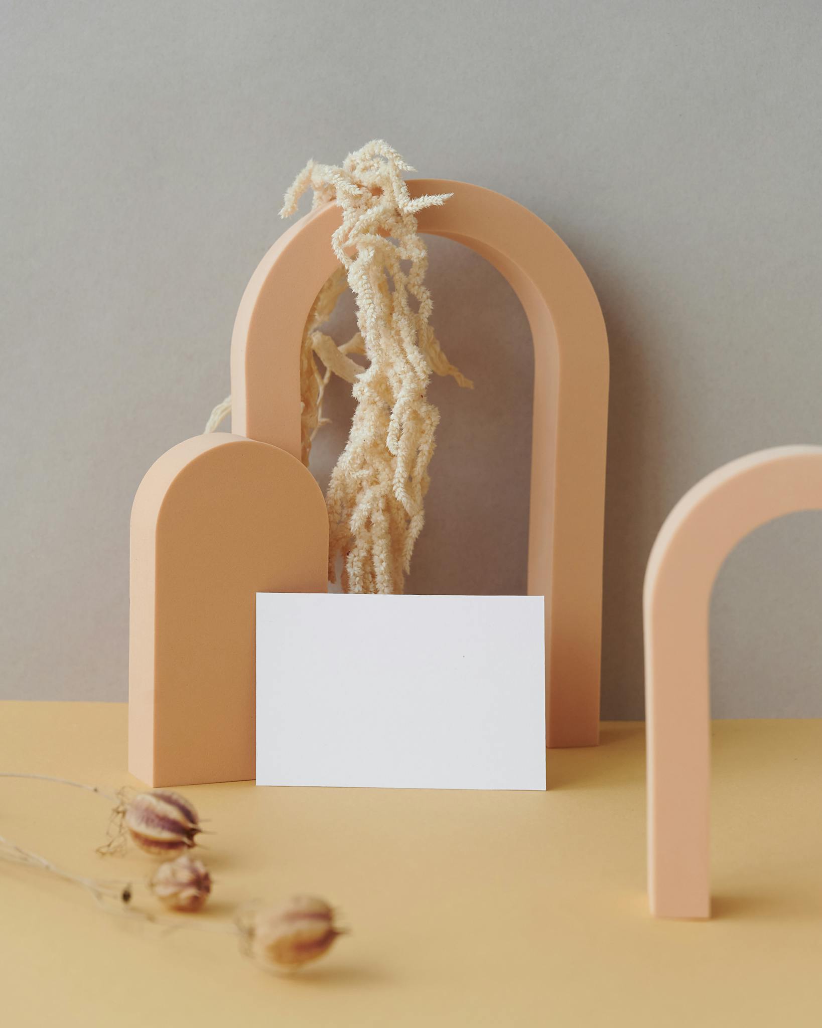 Minimalist business card mockup featuring modern arched structures and dried floral arrangement for a sophisticated presentation.